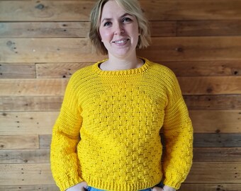 May include: A yellow crocheted sweater with a textured stitch pattern. The sweater has long sleeves and a round neckline.