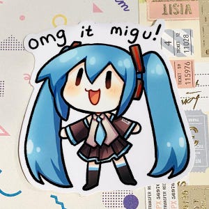 Könnte beinhalten: Ein Aufkleber mit einer Cartoonfigur mit blauen Haaren und dem Text "omg it migu!". Die Figur trägt ein braunes und schwarzes Outfit mit einer blauen Krawatte. Der Aufkleber befindet sich auf einem Hintergrund mit Tickets und dekorativen Elementen.