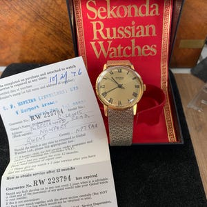 May include: A vintage Sekonda Russian watch in its original box. The watch has a gold-coloured face with Roman numerals and a mesh strap. A guarantee card is also present.