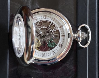 May include: Silver pocket watch with a partially open lid. The watch face is white with Roman numerals and a decorative inner mechanism. The watch has a silver chain loop and is set against a dark background.