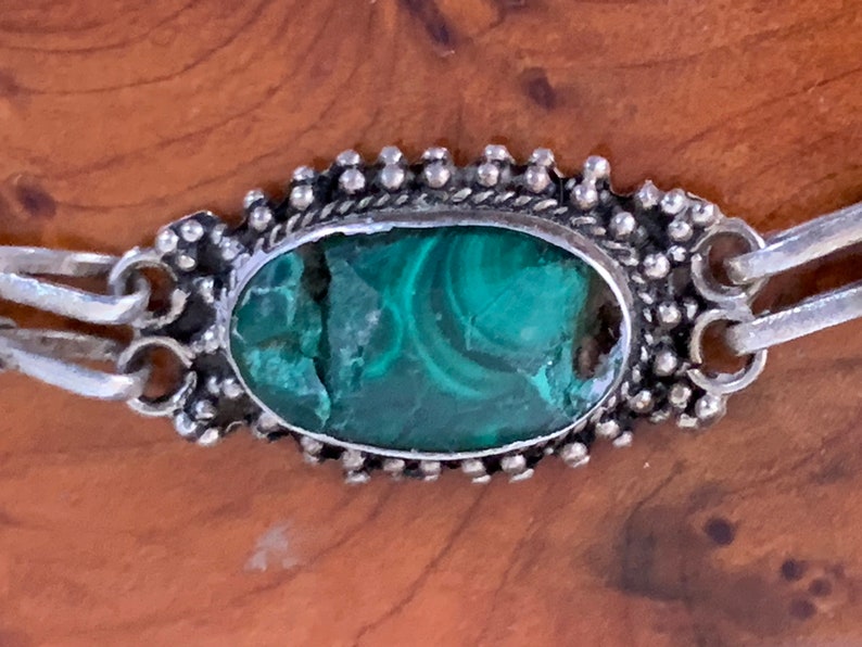 silver bracelet set with oval cabochon malachite stones within a burr-wood presentation case .