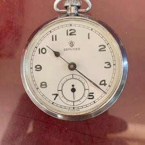 Peut inclure: Une montre de poche argentée avec des aiguilles noires et des chiffres romains. Le cadran de la montre porte les inscriptions "S Services" et "Foreign".