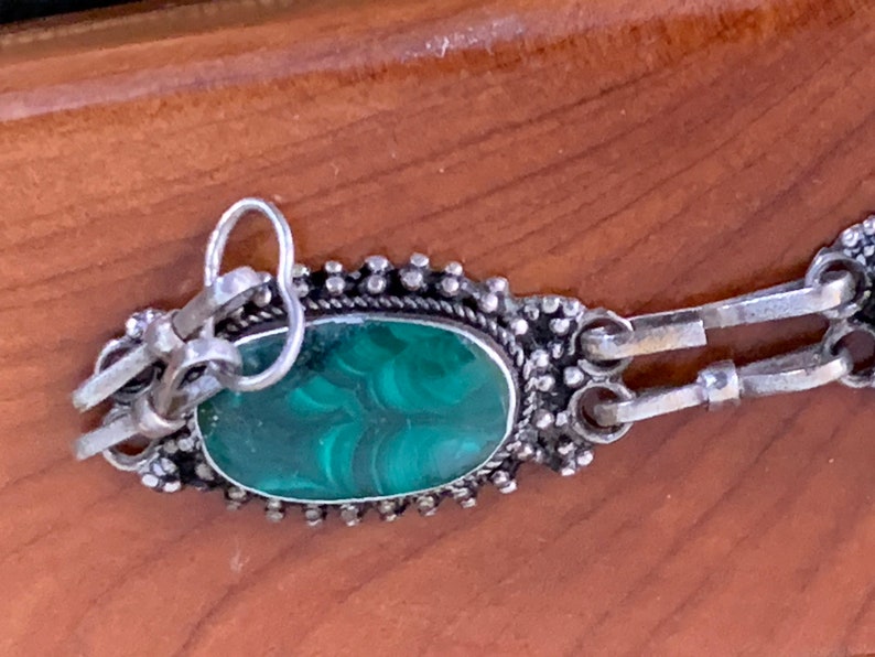 silver bracelet set with oval cabochon malachite stones within a burr-wood presentation case .