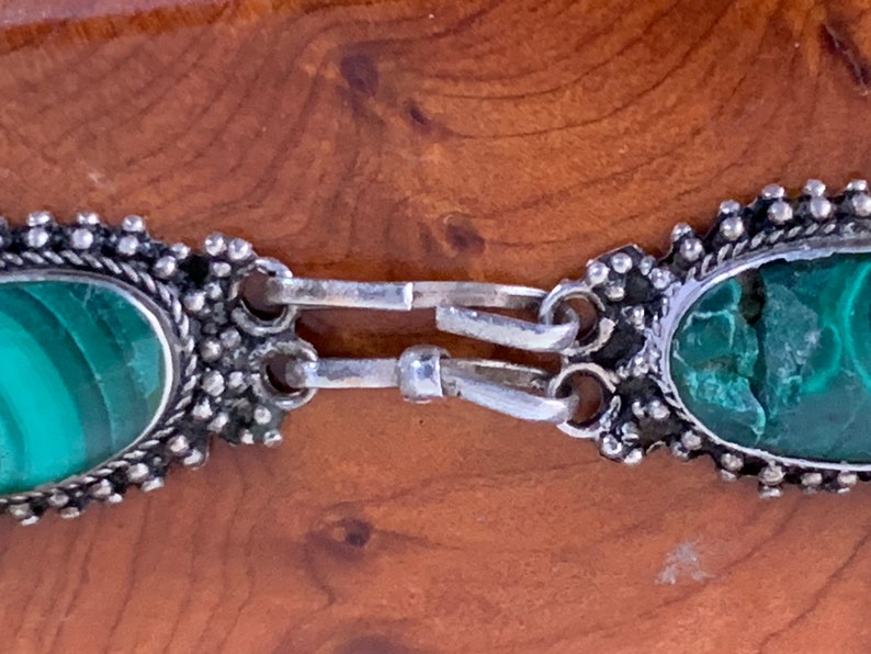 silver bracelet set with oval cabochon malachite stones within a burr-wood presentation case .