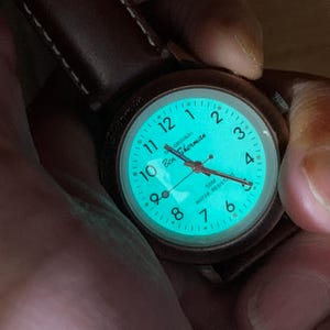 K&ouml;nnte beinhalten: Eine Ben Sherman-Uhr mit braunem Lederarmband. Das Zifferblatt leuchtet t&uuml;rkis und zeigt wei&szlig;e Ziffern und Zeiger. Die Uhr ist wasserdicht bis 50m.
