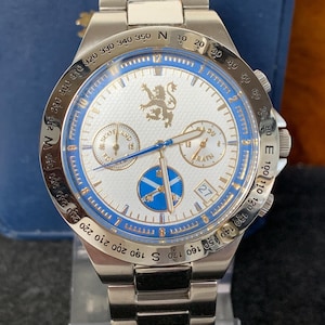 Puede incluir: Reloj de pulsera plateado con esfera blanca y detalles azules. El reloj presenta m&uacute;ltiples subesferas, una pantalla de fecha y un bisel giratorio con marcas de br&uacute;jula. La correa es de metal plateado.