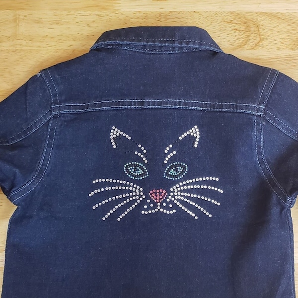 Kid's Bling Kitten Face denim jacket with long sleeves, pockets, and rhinestone buttons.