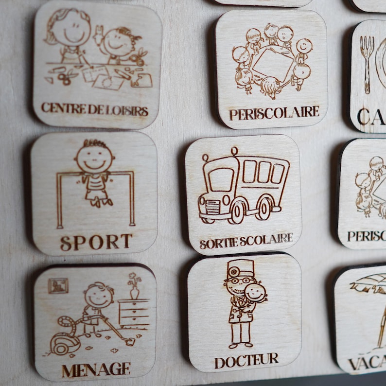May include: Wooden square tiles with illustrations and French text. The tiles feature images of a school bus, a doctor, a child playing sports, a child doing chores, a child at a daycare, a child at a school, and a child on vacation.