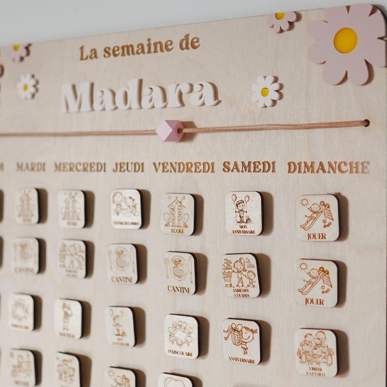 Pu&ograve; includere: Un calendario settimanale in legno con il nome "Madara" in alto. Il calendario ha i giorni della settimana in francese: Mardi, Mercredi, Jeudi, Vendredi, Samedi, Dimanche. Ogni giorno ha un piccolo quadrato di legno con un'immagine di un'attivit&agrave; quotidiana, come la scuola, il compleanno, il gioco e la mensa.