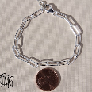 May include: A silver chain bracelet with a lobster clasp. The bracelet is about the size of a UK penny.