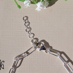 May include: Silver chain bracelet with a lobster clasp closure. The chain is made of oval links.
