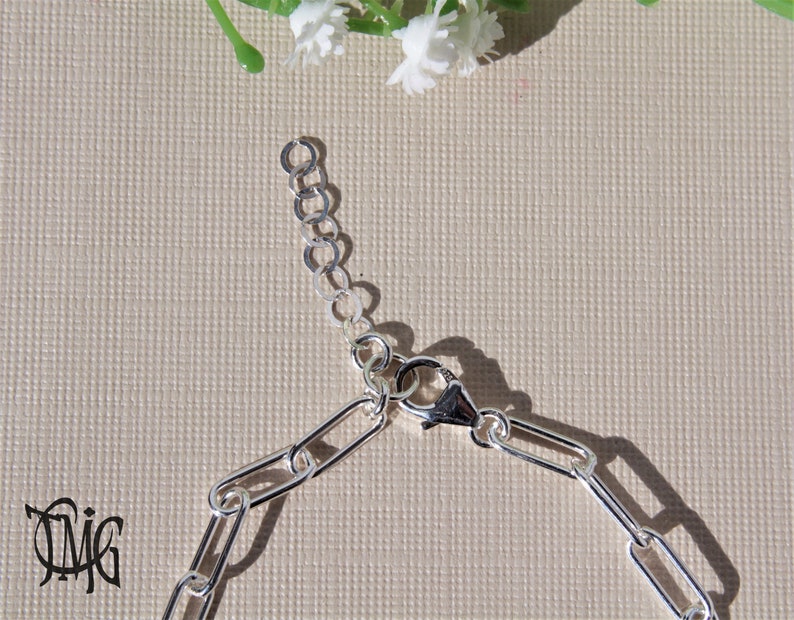 May include: Silver chain bracelet with a lobster clasp closure. The chain is made of oval links.