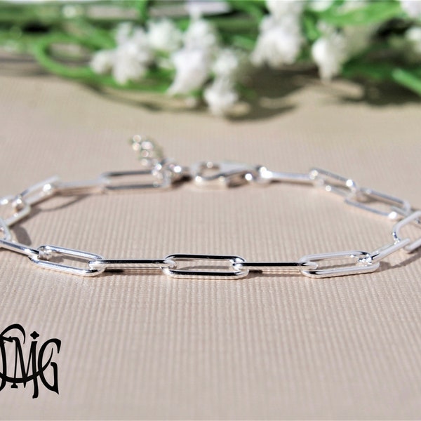 May include: A silver chain bracelet with a simple, linked design. The bracelet is made of small, rectangular links that are connected together to form a continuous chain.