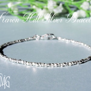 Puede incluir: Una delicada pulsera de plata con un diseño de cuentas facetadas. La pulsera se asegura con un pequeño cierre. El texto "Karen Hill Silver Bracelet" se muestra en cursiva.