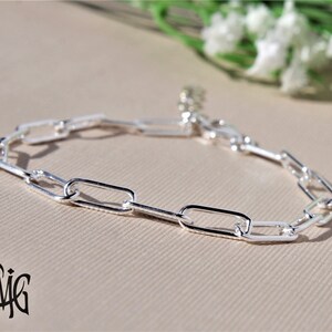 May include: A silver chain bracelet with a simple, rectangular link design.