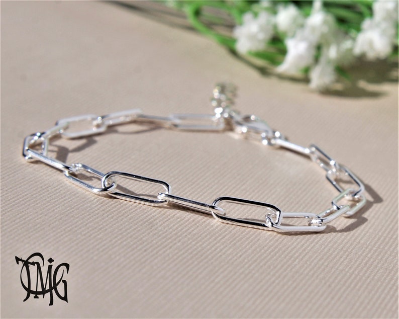 May include: A silver chain bracelet with a simple, rectangular link design.