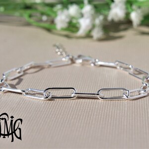 May include: A silver chain bracelet featuring a simple, rectangular link design. The bracelet is crafted from polished silver and has a secure clasp.