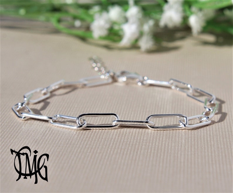 May include: A silver chain bracelet featuring a simple, rectangular link design. The bracelet is crafted from polished silver and has a secure clasp.