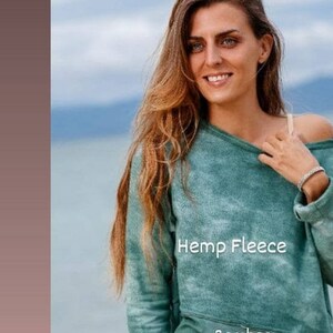 May include: A woman wearing a green hemp fleece and bamboo blend sweatshirt with a tie-dye pattern. The sweatshirt has a relaxed fit and a scoop neck.