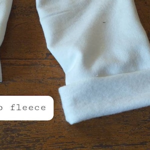 May include: Close-up of soft, white bamboo fleece fabric. The fabric is folded and the edges are visible.