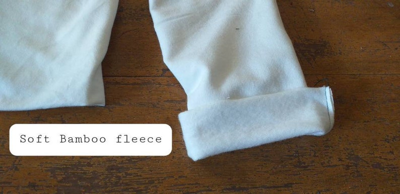 May include: Close-up of soft, white bamboo fleece fabric. The fabric is folded and the edges are visible.
