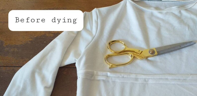 May include: A white long-sleeved shirt with a pair of gold scissors on top of it. The text "Before dying" is written on a white rectangle in the top left corner of the image.