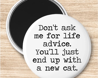 May include: A white round magnet with the text "Don't ask me for life advice. You'll just end up with a new cat." The magnet has a black magnetic backing and a silver border.