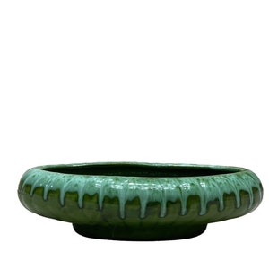 May include: A large, oval-shaped green ceramic planter with a white glaze dripping down the sides. The planter has a wide, shallow base.