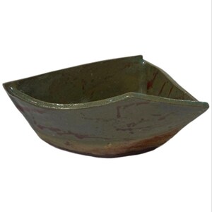 May include: A triangular ceramic bowl with a glossy olive green glaze on the interior and upper exterior, transitioning to a raw, unglazed reddish-brown clay base. The bowl features a wide, open top with distinct angled corners and a smooth finish.