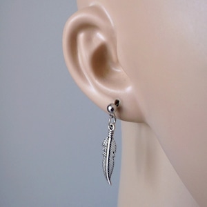 Puede incluir: Pendientes de plumas colgantes de plata. Los pendientes se muestran en la oreja de un maniquí.