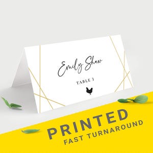 Pu&ograve; includere: Un segnaposto piegato bianco con linee geometriche dorate e il nome "Emily Shaw" in elegante corsivo. Sotto, si legge "Table 3" con una piccola silhouette di pollo. Le parole "PRINTED FAST TURNAROUND" sono stampate su sfondo giallo.