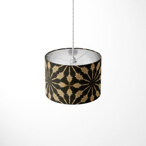 May include: A black and gold patterned lampshade with a white cord hanging from the ceiling.