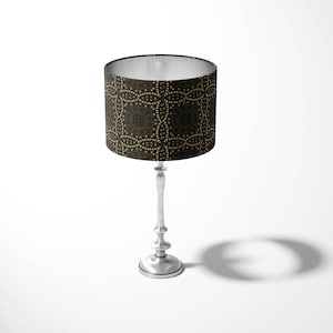 May include: A silver table lamp with a black and gold patterned lampshade. The lampshade has a geometric design.