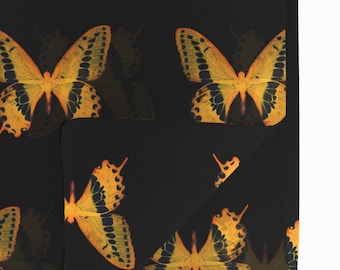 May include: Black fabric with a repeating pattern of yellow and orange butterflies. The fabric is folded in the center.