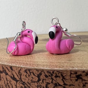 May include: Pink flamingo earrings made of polymer clay with silver hooks. The earrings are approximately 2.5 cm tall.