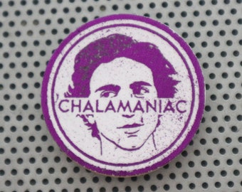 May include: A purple round sticker with a white image of a person's face and the text "CHALAMANIAC" in white.