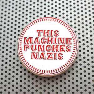 Deze machine ponst nazi-speld / 1,5" pinback-badge of -knop. Handgemaakte antifa-typografieprint in metallic rode folie op wit