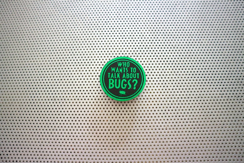 May include: A green and black round sticker with the text "WHO WANTS TO TALK ABOUT BUGS?" on a white background with a pattern of small holes.