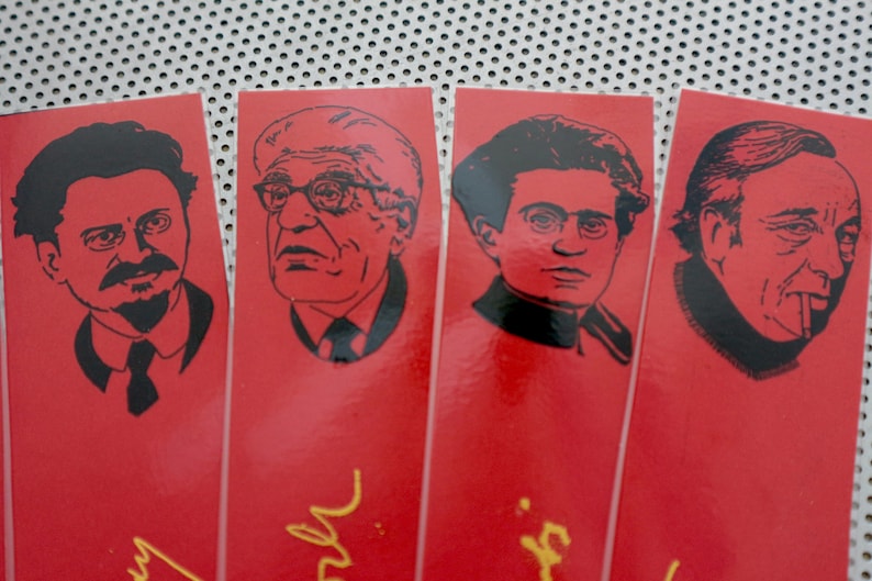 May include: Four red bookmarks with black and white illustrations of men's faces. Each bookmark has a gold signature at the bottom.