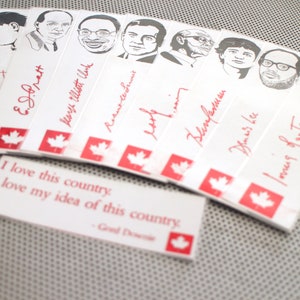 May include: A collection of white bookmarks with red maple leaf designs and black and white illustrations of famous Canadians. The bookmarks feature the signatures of the individuals pictured. The text "I love this country. I love my idea of this country." is printed on a separate bookmark.