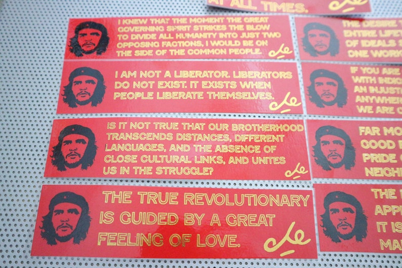 May include: A collection of red and gold stickers with quotes from Che Guevara. The stickers feature a portrait of Che Guevara and the text "Che" in gold lettering. The quotes include "I knew that the moment the great governing spirit strikes the blow to divide all humanity into just two opposing factions, I would be on the side of the common people."