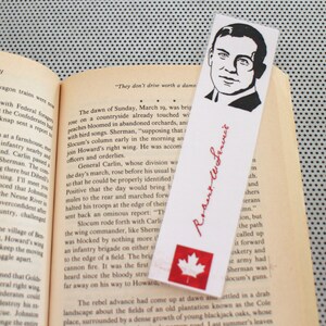 May include: A bookmark featuring a black and white illustration of a man with a mustache and a signature that reads "Robert E. Lee." The bookmark also features a red maple leaf on a white background.