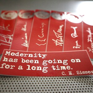 May include: Red bookmarks with white text and signatures. A rectangular bookmark displays the quote "Modernity has been going on for a long time" by C. H. Sisson. The bookmarks are arranged on a perforated metal surface.