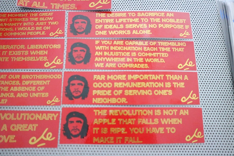 May include: Eight red and yellow stickers with a portrait of Che Guevara and a quote in gold lettering. The quotes are: "At all times", "The moment the great", "Liberator, liberators", "What our brotherhood", "Revolutionary, a great", "The desire to sacrifice", "If you are capable", "Far more important".