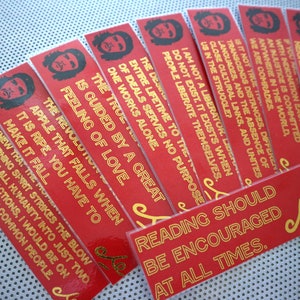 May include: A set of ten red bookmarks with gold text featuring quotes from Che Guevara. The bookmarks feature a silhouette of Che Guevara's face.