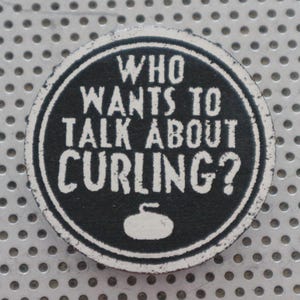May include: A circular badge with the text "WHO WANTS TO TALK ABOUT CURLING?" in white on a black background. A white curling stone graphic is at the bottom. The badge has a distressed, vintage appearance.