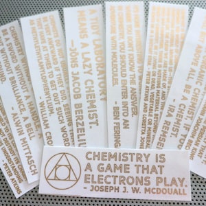 Puede incluir: Un conjunto de diez pegatinas de lámina dorada con citas inspiradoras sobre química. Las pegatinas presentan una variedad de citas, que incluyen "Un laboratorio ordenado significa un químico perezoso." y "La química es un juego que juegan los electrones."