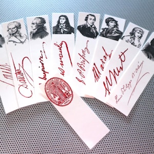 May include: A collection of white bookmarks featuring black and white illustrations of famous people. Each bookmark has a handwritten signature in red ink. The bookmarks are arranged in a fan shape with a red wax seal in the centre.