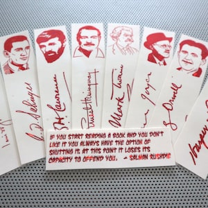 May include: A collection of white bookmarks with red illustrations of famous authors and their signatures. A small rectangular card with a quote by Salman Rushdie is also included.