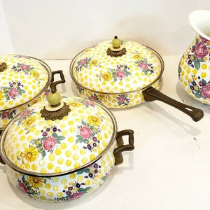 May include: A set of vintage kitchenware featuring a yellow polka dot pattern with floral accents. The set includes three lidded pots and a pitcher. The pots have brown handles and decorative brass-toned accents. The pitcher has a white interior.